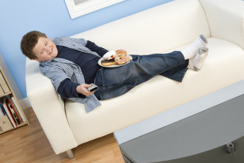 عکس کودک چاق و کیک در حال تماشای تلویزیون