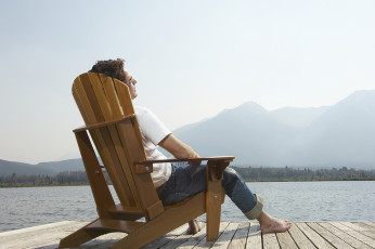 عکس مرد روی صندلی کنار دریاچه