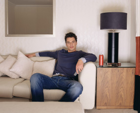 عکس مرد روی کاناپه در حال تماشا کردن تلویزیون